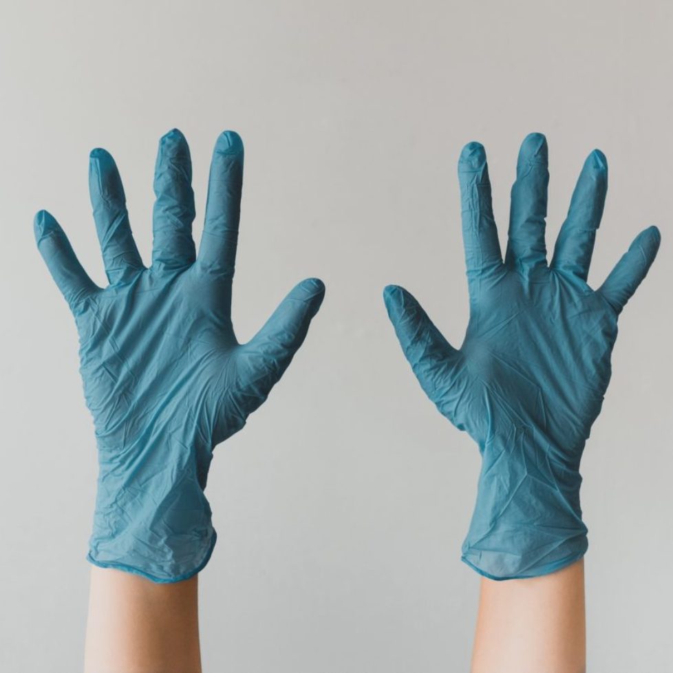 An image of a White person wearing blue medical gloves with their fingers spread wide.